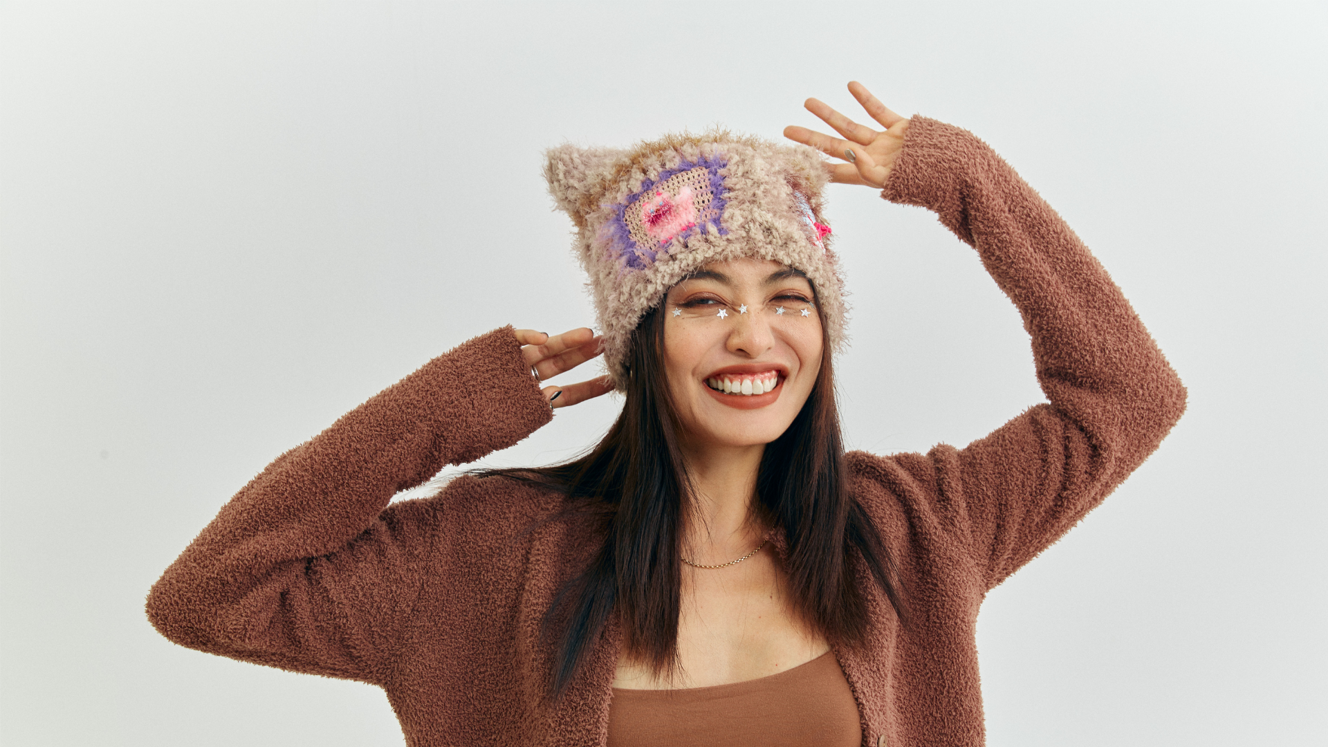 Smiling woman modeling a cozy handmade crochet cat-ear hat, embodying the joyful and artistic spirit of FeekyStore’s dopamine aesthetic collection.
