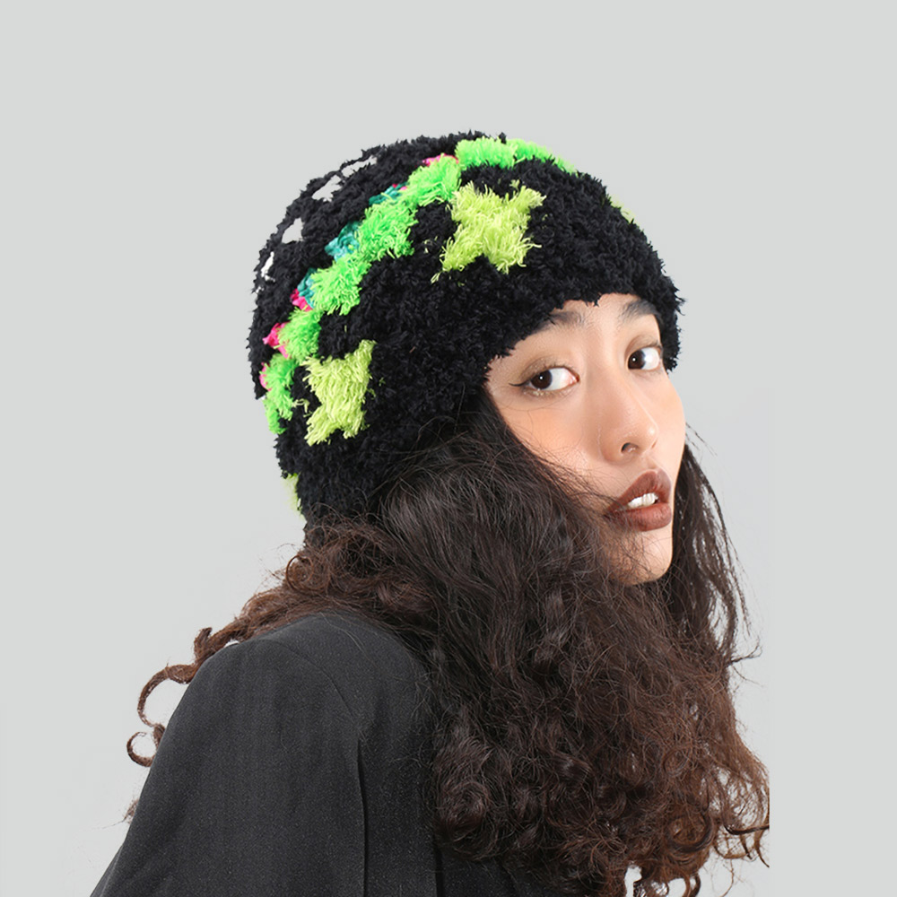 Side view of a model wearing the black woolen crochet hat, showcasing the vibrant neon green cross star pattern against the fuzzy black yarn.