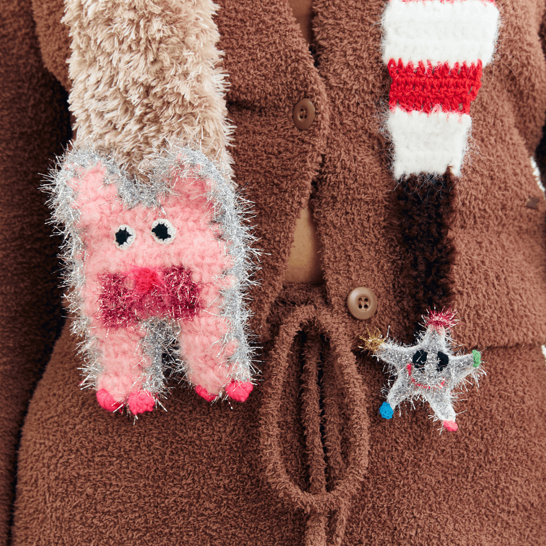 Close-up detail of FeekyStore fluffy cat star scarf featuring a pink cat patch and a star charm on striped ends against a white studio background.