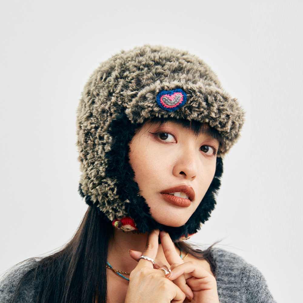 Close-up front shot of the Cloud-Pooch Crochet earflap hat on a model, illustrating the dense and warm handmade loop-stitch yarn texture.