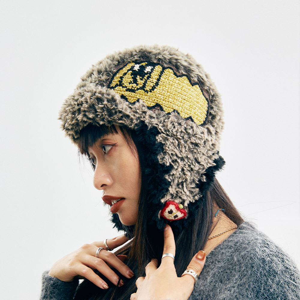 Side profile view of the Cloud-Pooch Crochet Aviator Hat, highlighting the unique yellow patch with a cute dog and cloud pattern on the textured yarn.