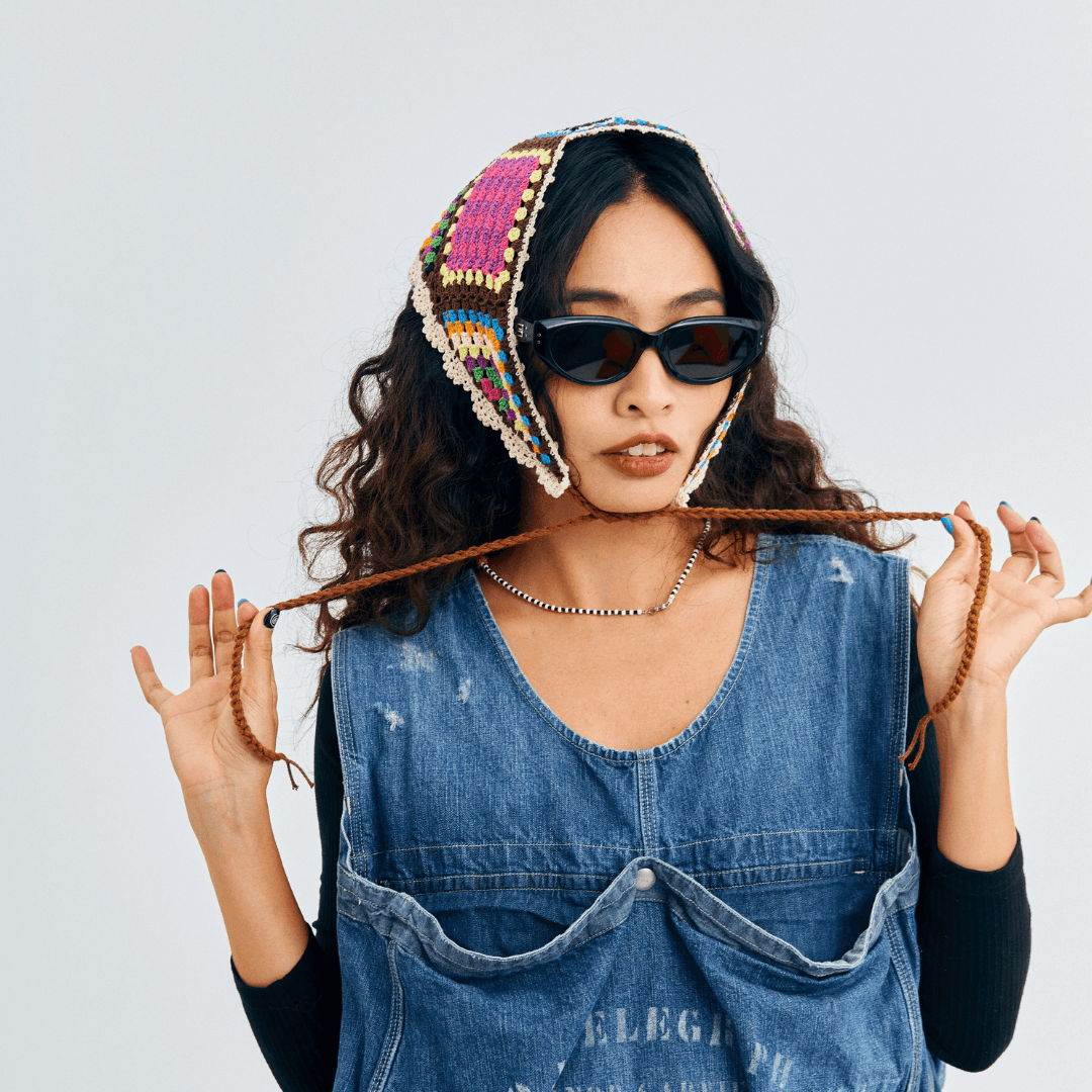 FeekyStore colorful crochet triangle headscarf modeled by a woman in a denim outfit holding the strap ties, in a clean studio portrait.
