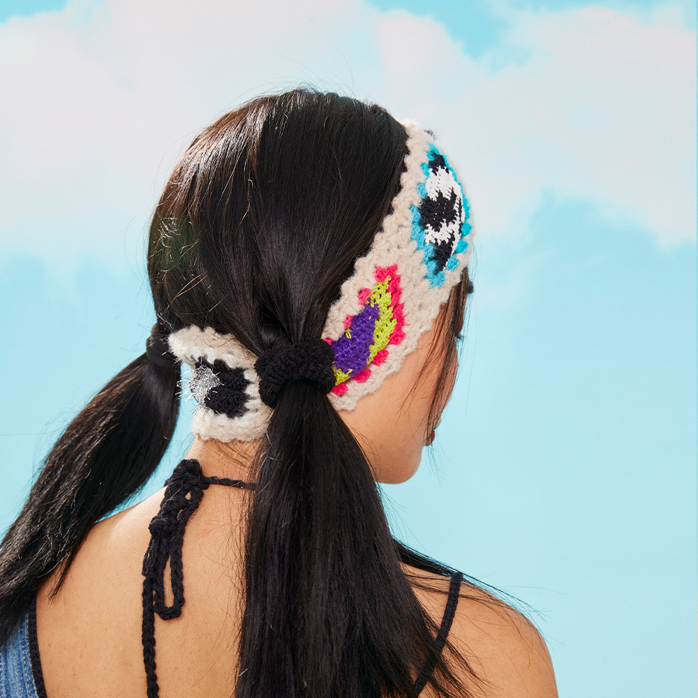 Back view of the Cow Velvet Crochet Headband on a model with twin ponytails, illustrating the comfortable textured fit and colorful side stitch rows.