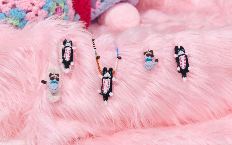 {"default":"A collection of FEEKY crochet cat-themed accessories placed on a soft pink furry background for a whimsical and cozy feel."}
