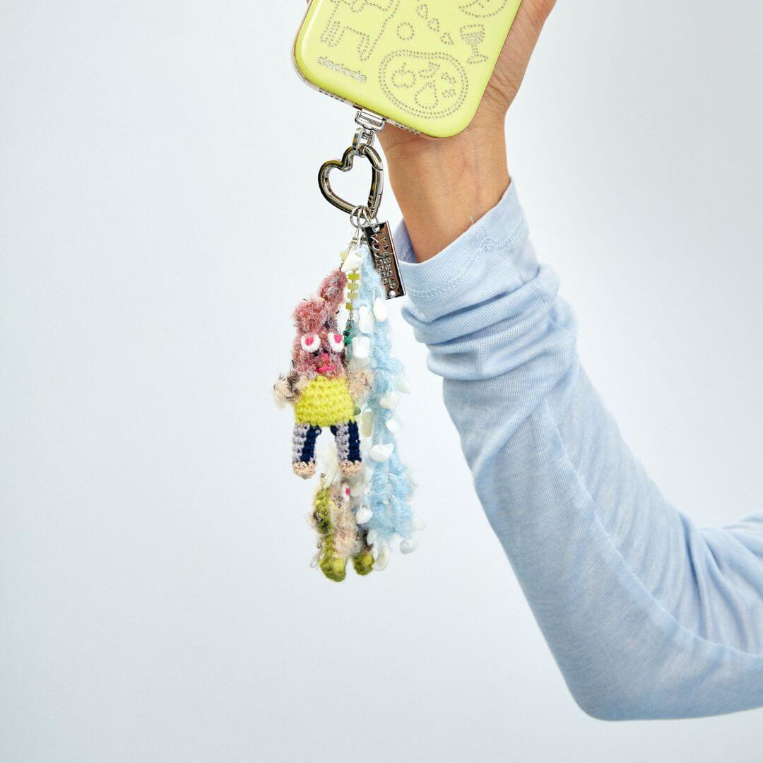 A close-up lifestyle shot of the hand-crocheted Bunny & Pony charm, demonstrating its size and tactile texture when held.