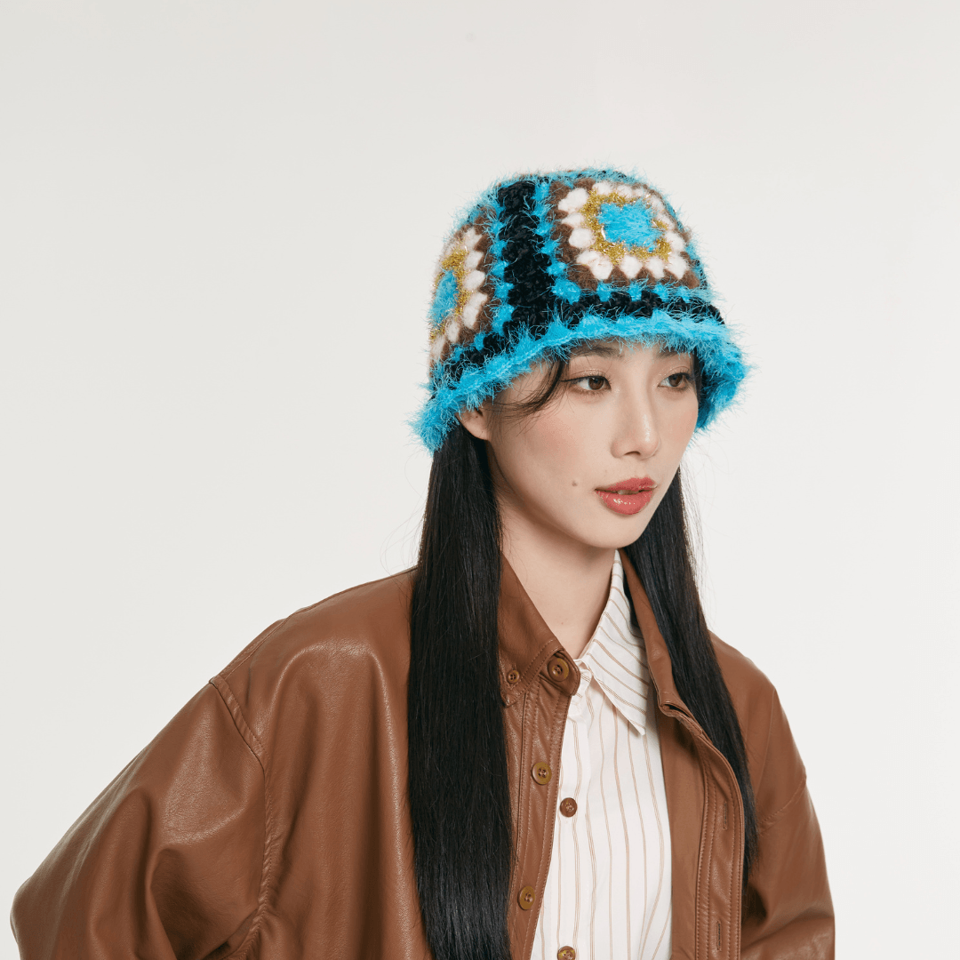 FeekyStore crochet Fisherman Hat featuring blue and black geometric granny square patterns, modeled by a woman in a brown leather jacket against a clean studio background.