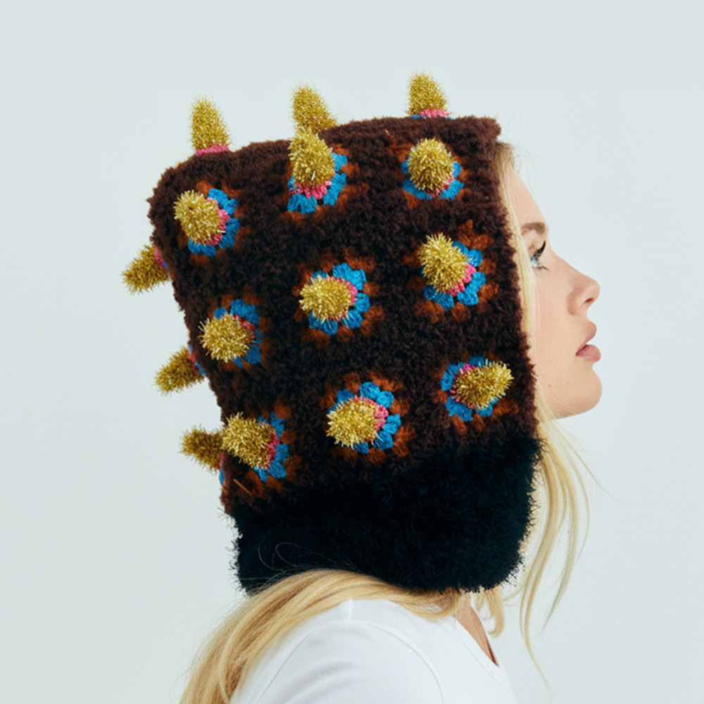 Side profile view of the Fortune Bomb Crochet Hat showing the textured crochet spikes and unique square hood silhouette.