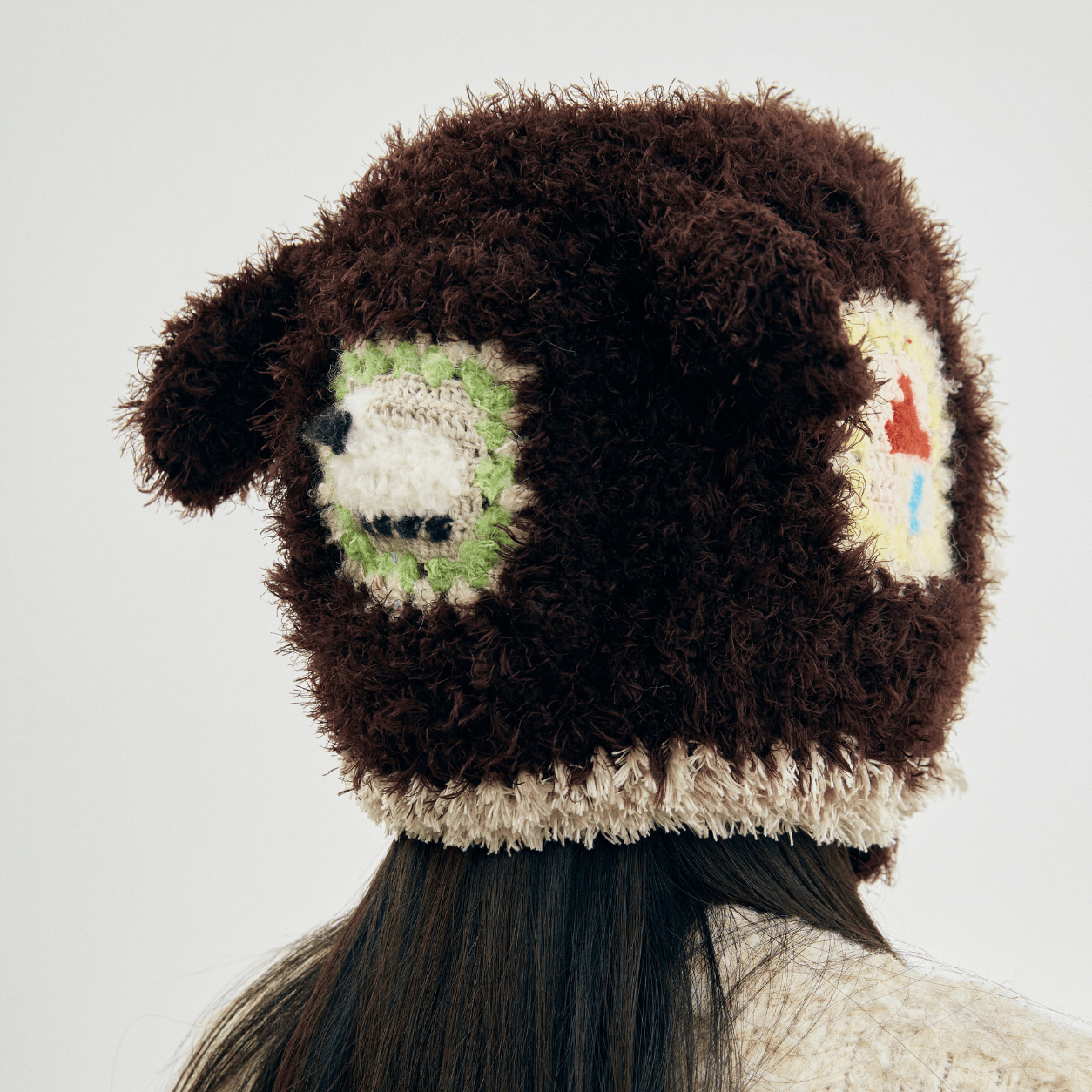 Back view of the Little Lamb Patchwork Hat featuring fuzzy brown crochet, cream edging, and colorful handmade patches.