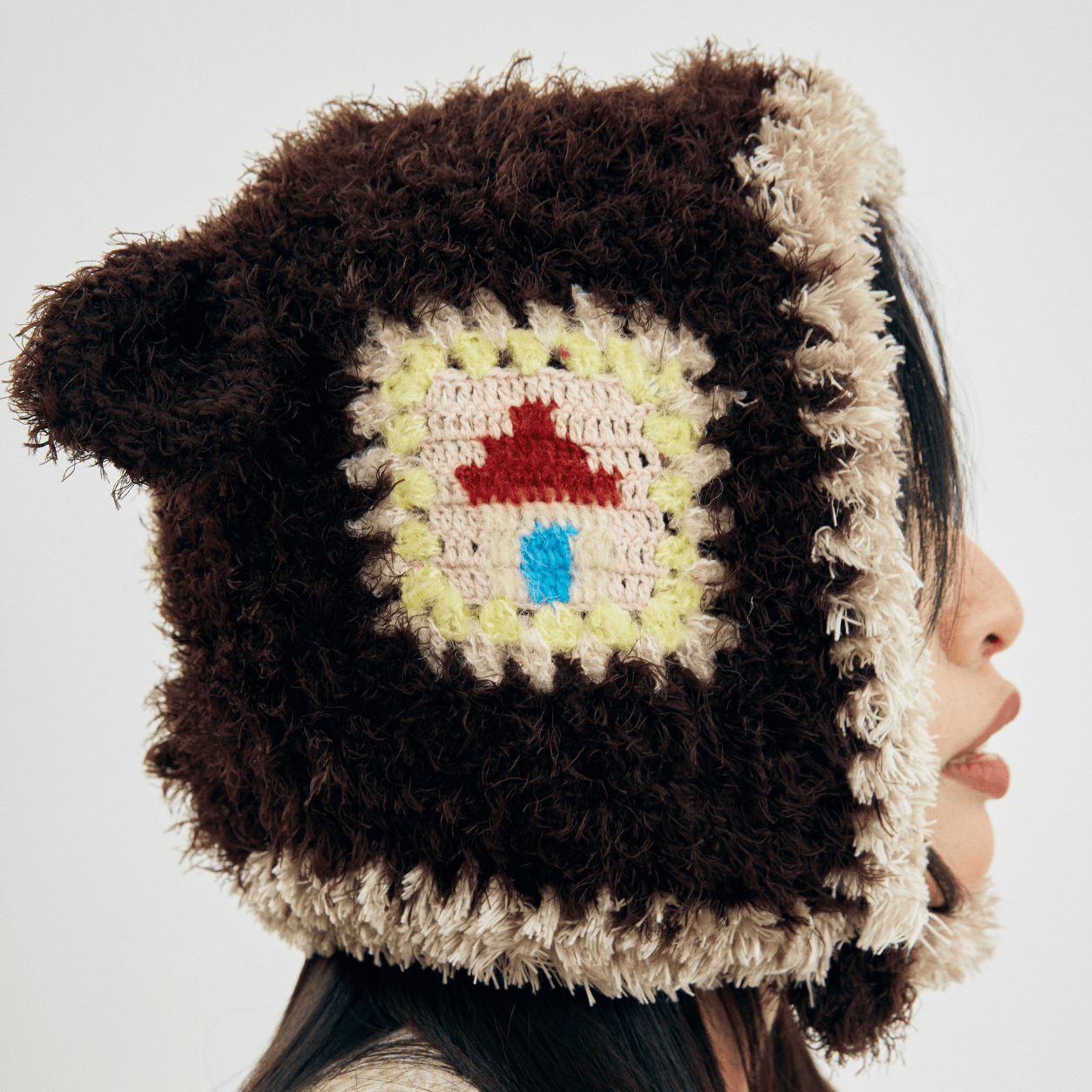 Side close-up of the Little Lamb Patchwork Hat showing its colorful crochet patchwork, fluffy texture, and lamb ear.