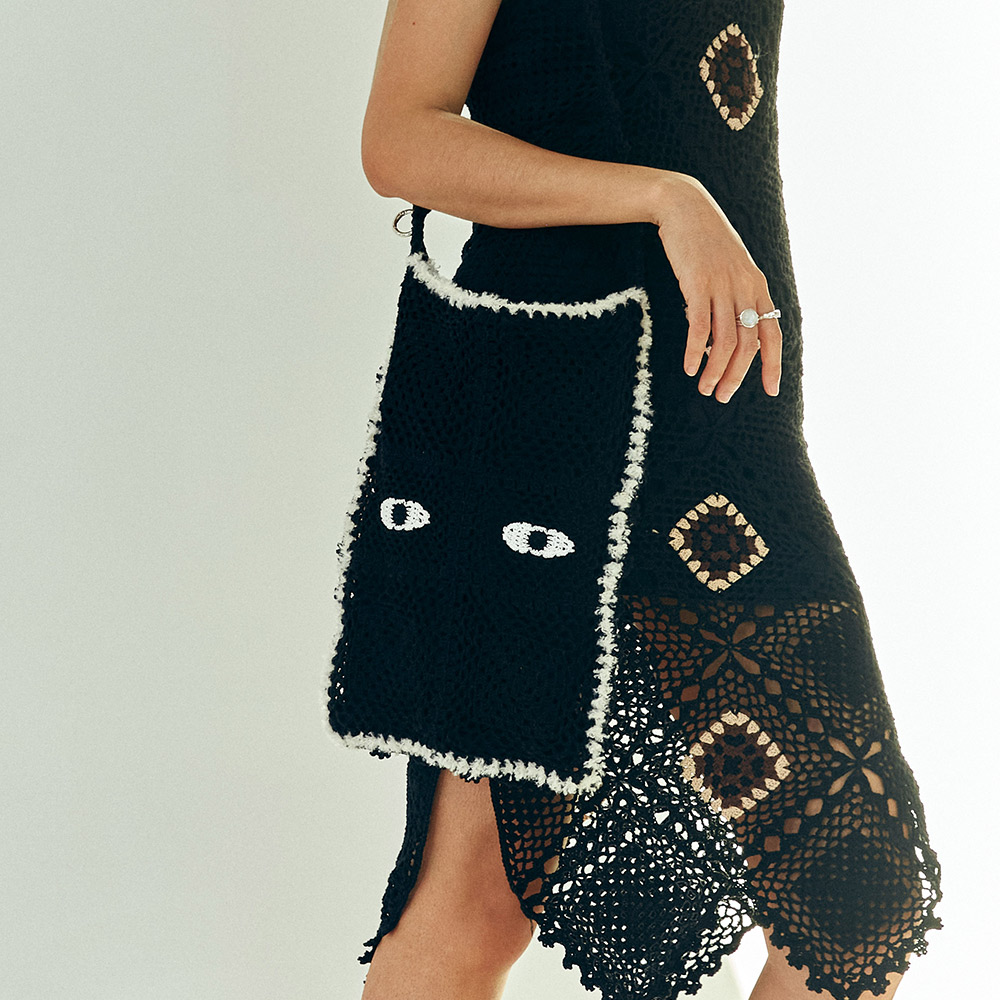 A model styling the black cat eyes side of the textured crochet shoulder bag, paired with an alternative black lace outfit for a gothic chic look.