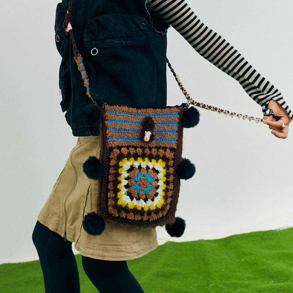 Back view of the reversible puppy theme crochet bag on a model, highlighting the alternative dark earth-tone geometric stitch block layout.