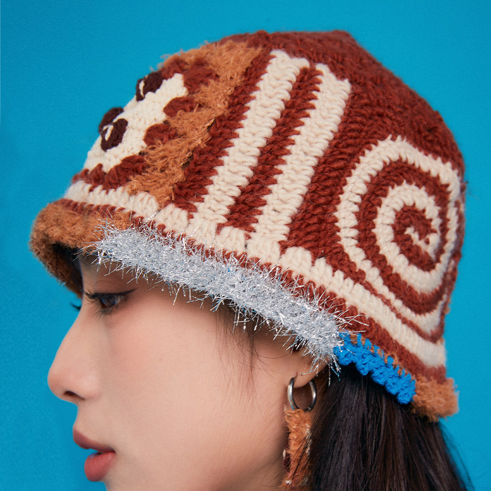Side profile view of the Refreshing Coffee Crochet Hat on a model, displaying the spiral pattern work and the fuzzy grey contrast textured brim.