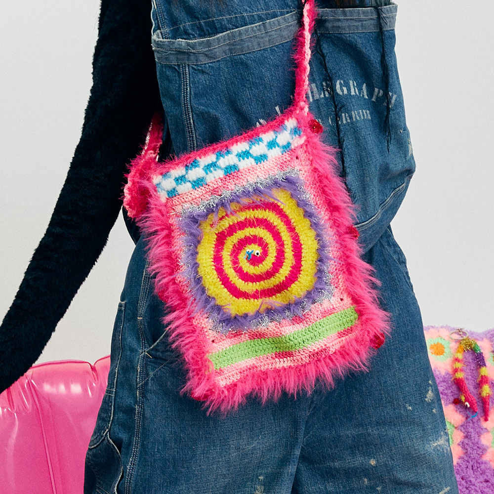 Back view of the reversible crochet bag on a model, showcasing the eye-catching pink and yellow spiral stitch pattern block.