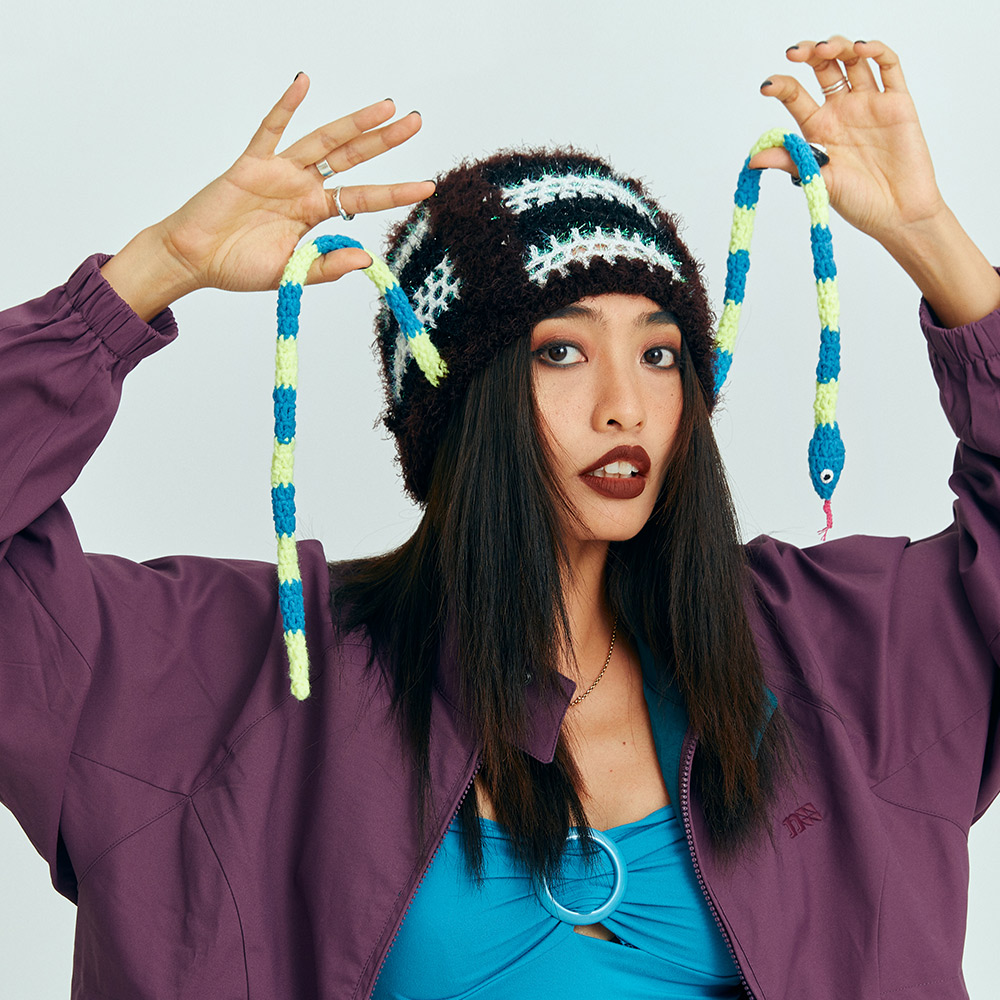 Lifestyle shot of a model holding up the long, playful snake-shaped crochet braids, demonstrating the unique design of the winter accessory.