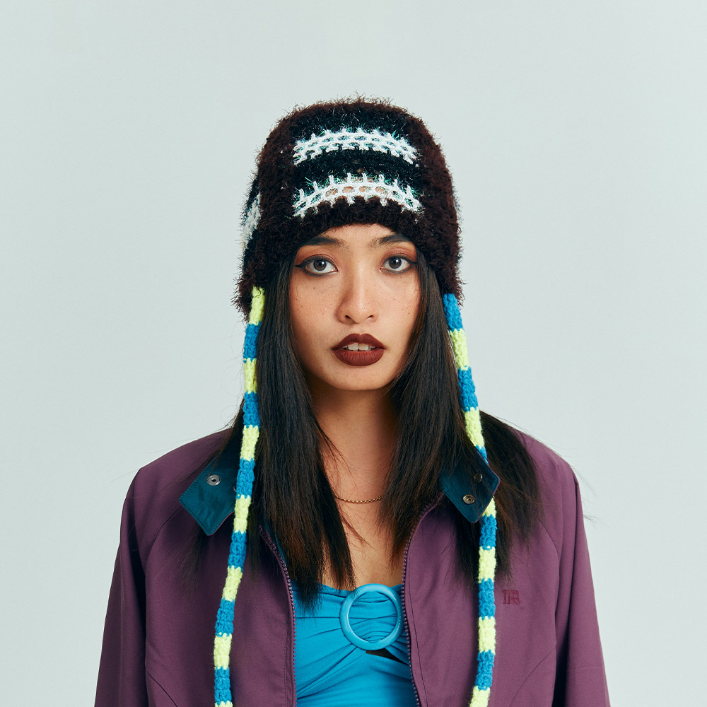 Front view of a model wearing the dark brown Snake Crochet beanie with two colorful snake-like braids dangling down the sides.