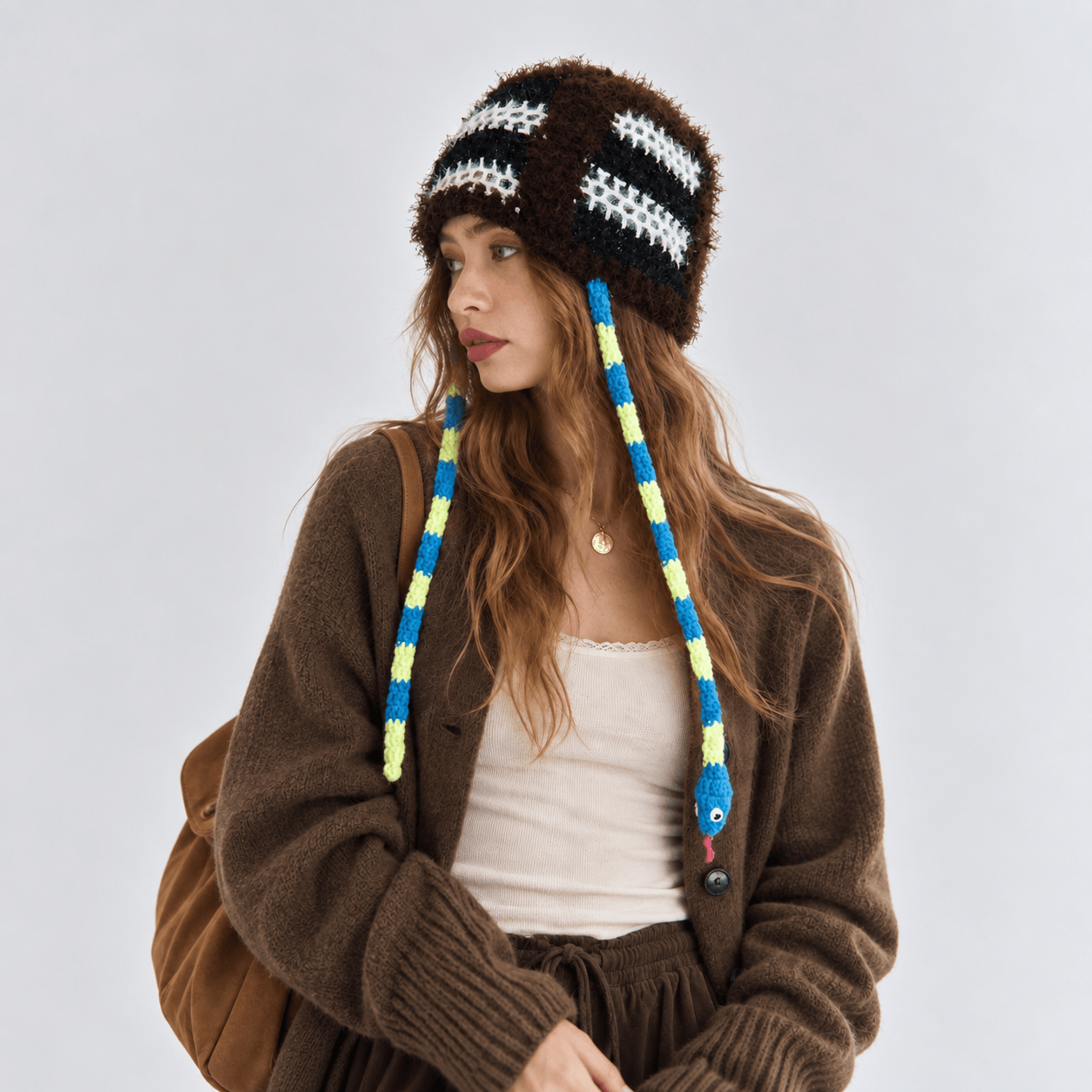 FeekyStore brown fuzzy snake hat featuring distinctive blue and yellow striped long braids, modeled in a clean studio setting.
