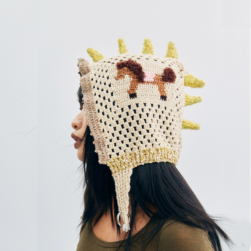 Side profile view of the Unicorn Pony Crochet Hat, highlighting the open-work mesh crochet stitch and the playful dinosaur-like yellow spikes.