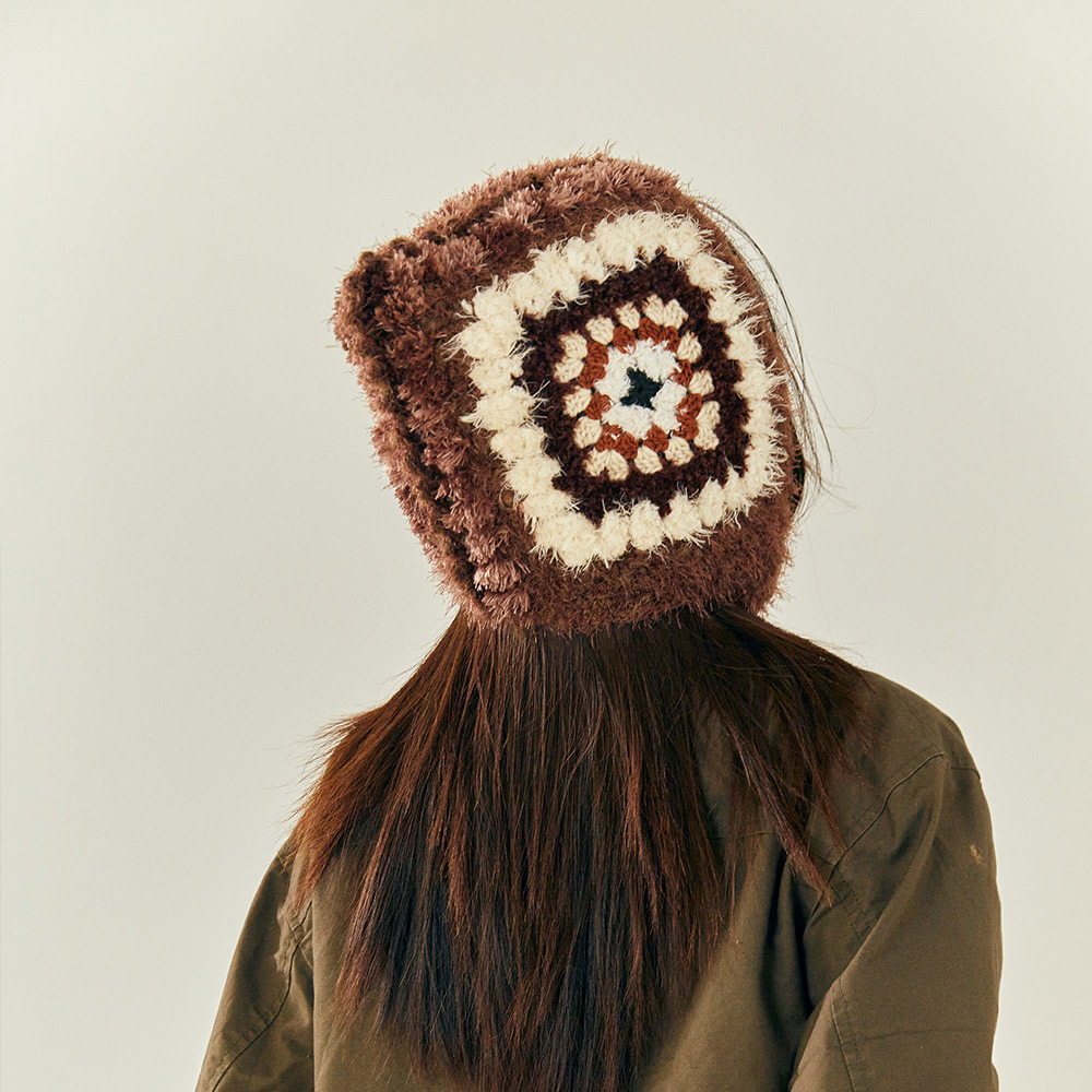 An angled back-three-quarter view of the Vintage Grid Crochet Hat on a model, illustrating the square hood structure.