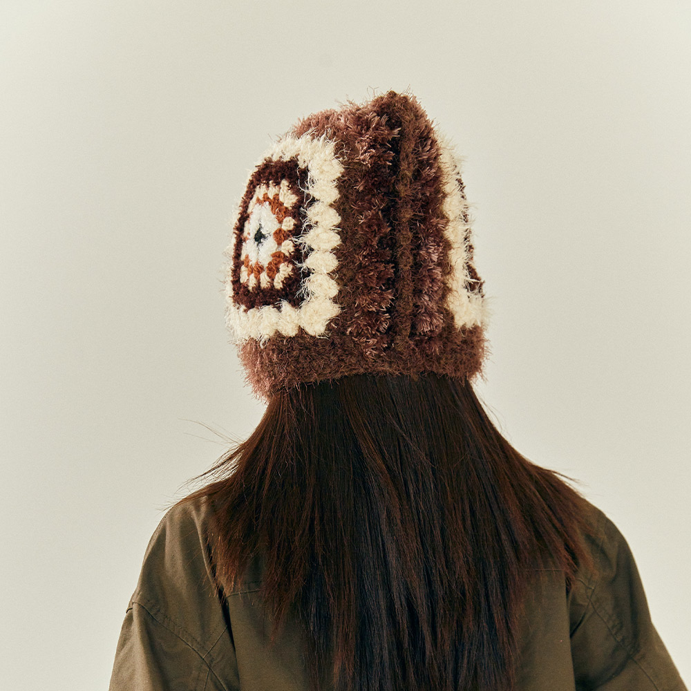 Front view of a model wearing the Vintage Grid Crochet Hat, featuring cozy earflaps and long dangling chin ties.