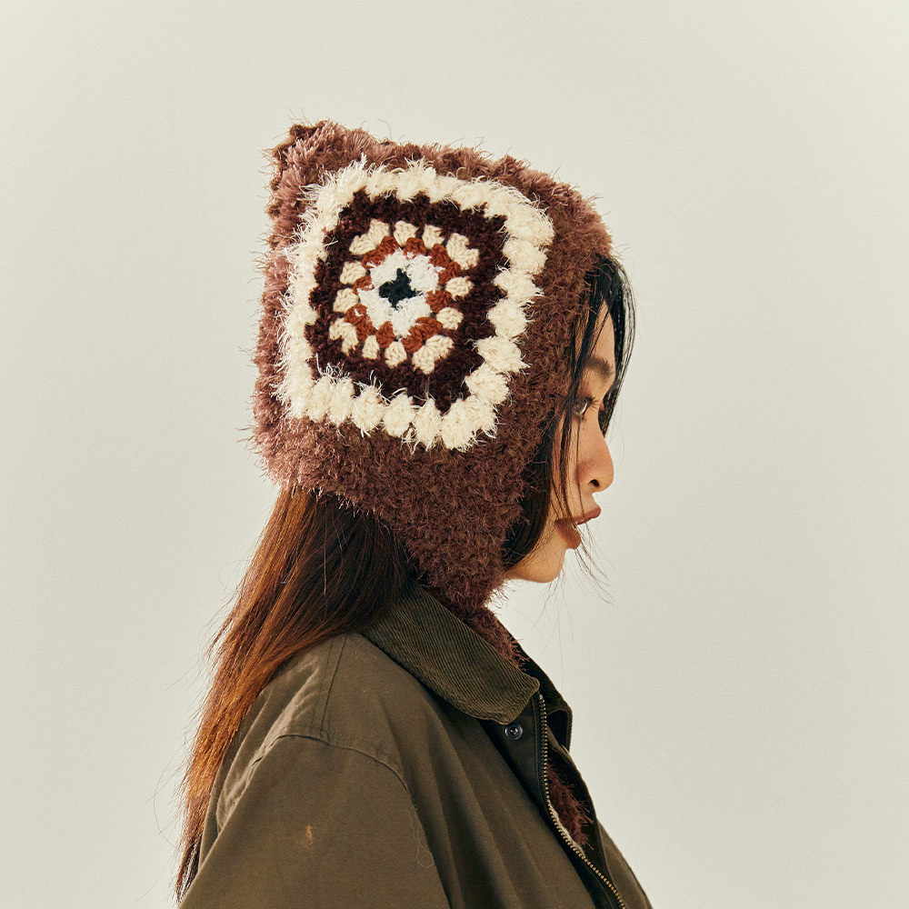 Side profile view of a model wearing the Vintage Grid Crochet Hat, showcasing the classic brown and white granny square pattern.