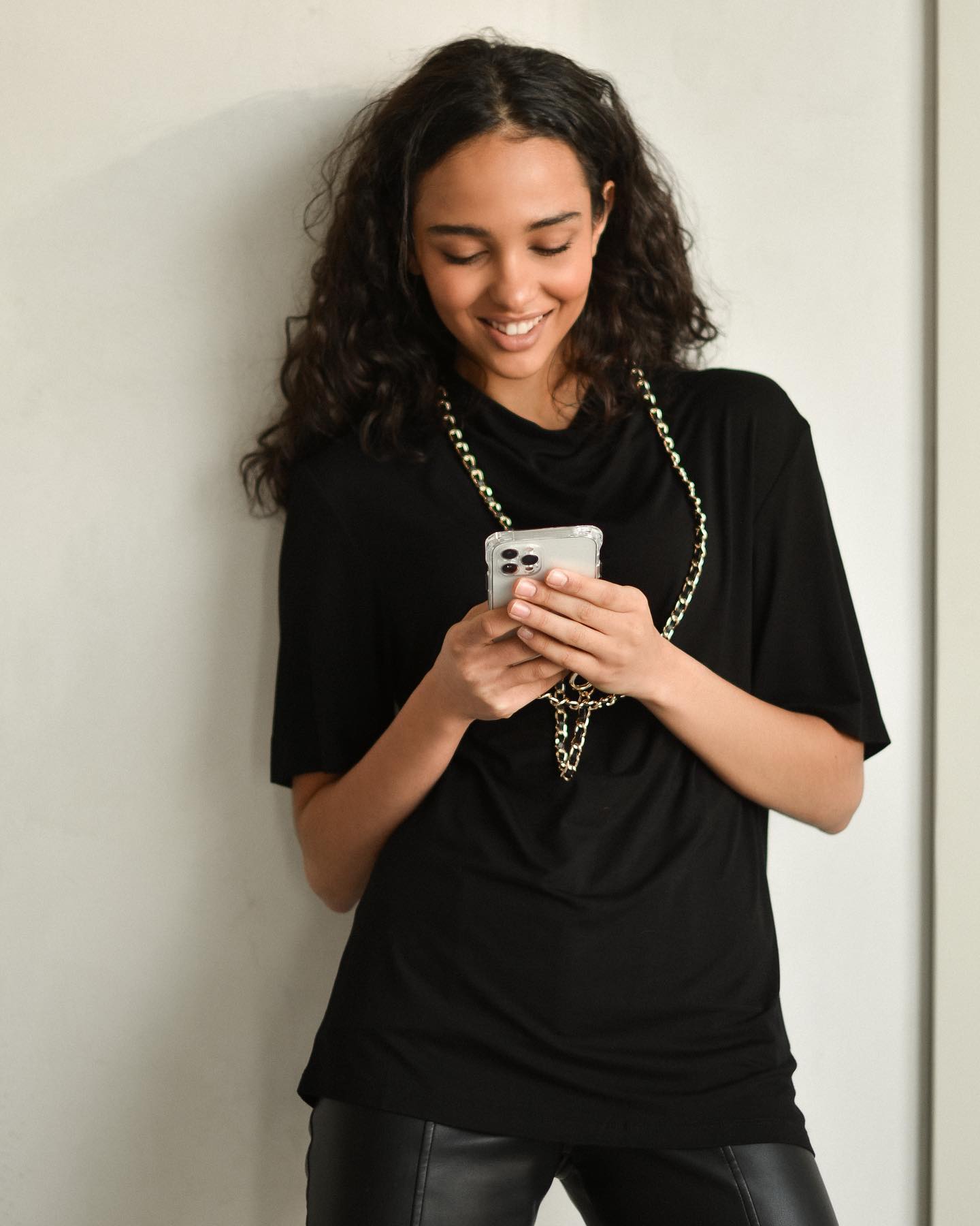 Stylish woman holding an iPhone with a trendy luxury case, showcasing modern fashion trends for 2025.