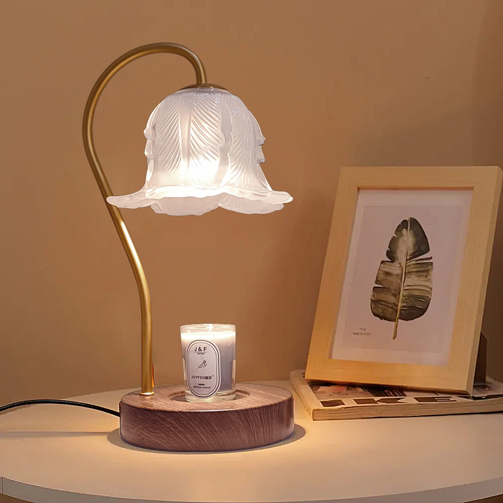 An aromatherapy candle floral table lamp sitting next a picture decoration on a table.