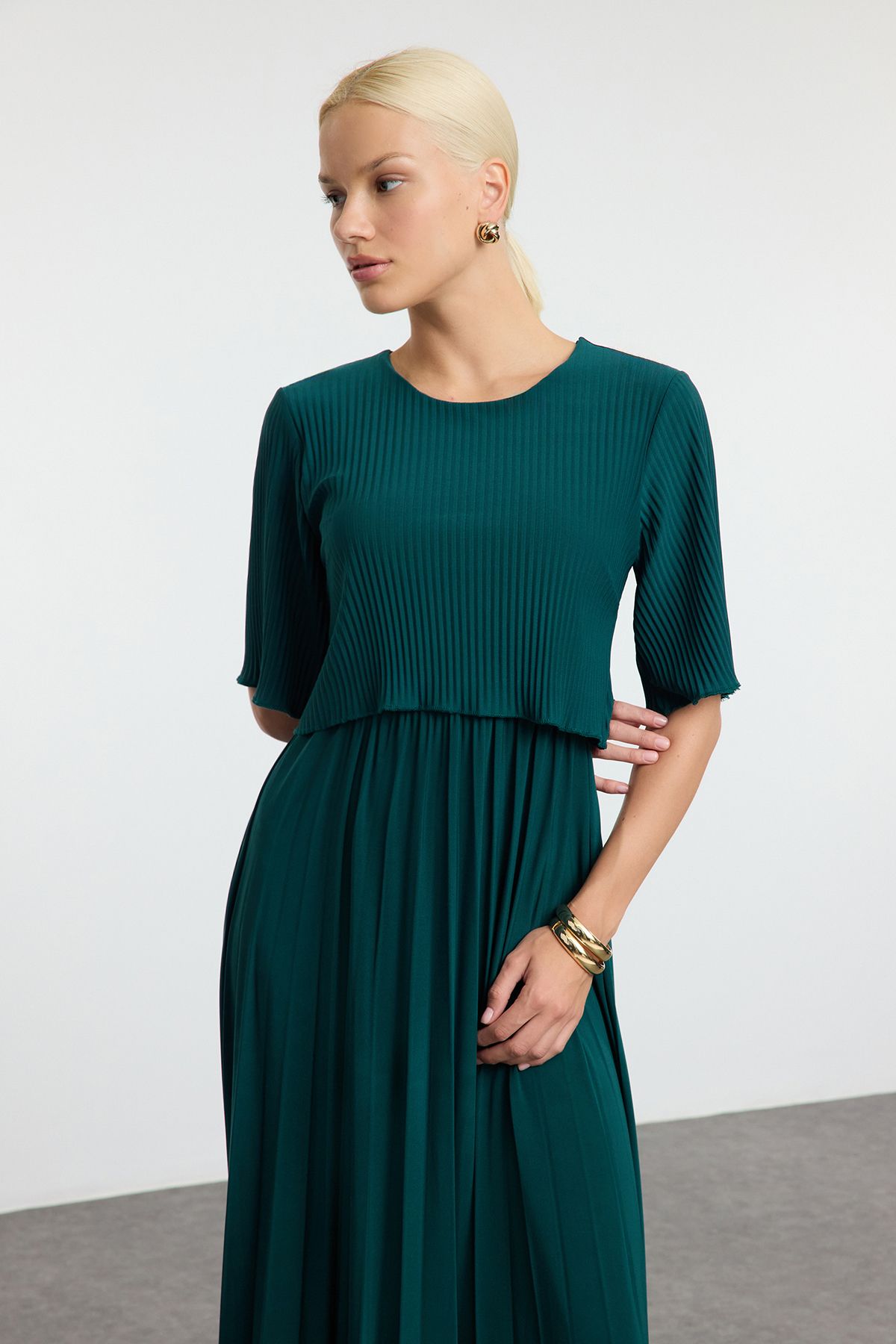 Woman wearing a teal pleated midi dress as a wedding guest