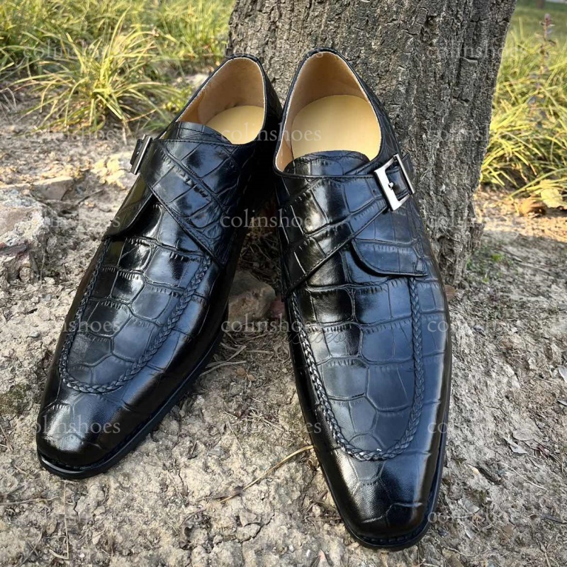 Main view of black crocodile leather monk strap loafers with silver buckle.