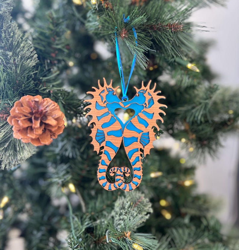 可能包括:一个木制圣诞装饰品,形状为两只蓝棕色海马面对面,尾巴交缠在一起。海马身上绘有蓝白相间的条纹图案。