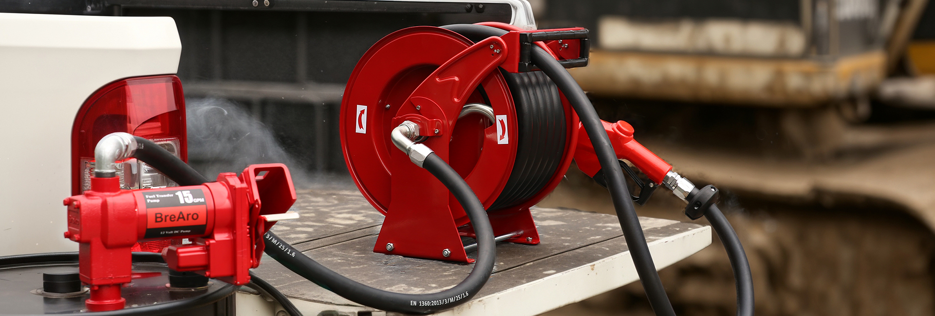 Red fuel transfer hose reel and pump system mounted on a sturdy platform, designed for efficient oil transfer applications in industrial and everyday use, with durable construction and high performance.