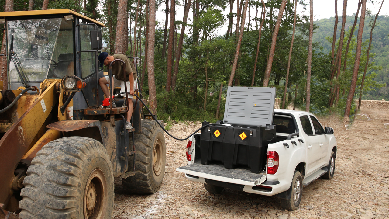 Portable fuel transfer tank refueling heavy machinery in a forest setting, showing efficient fuel management.
