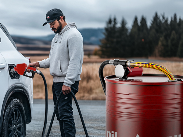 A man fueling his vehicle using the Brearo 10 GPM fuel transfer pump from a barrel. The image highlights the practical use of the pump in outdoor environments for fast and stable fuel transfer.