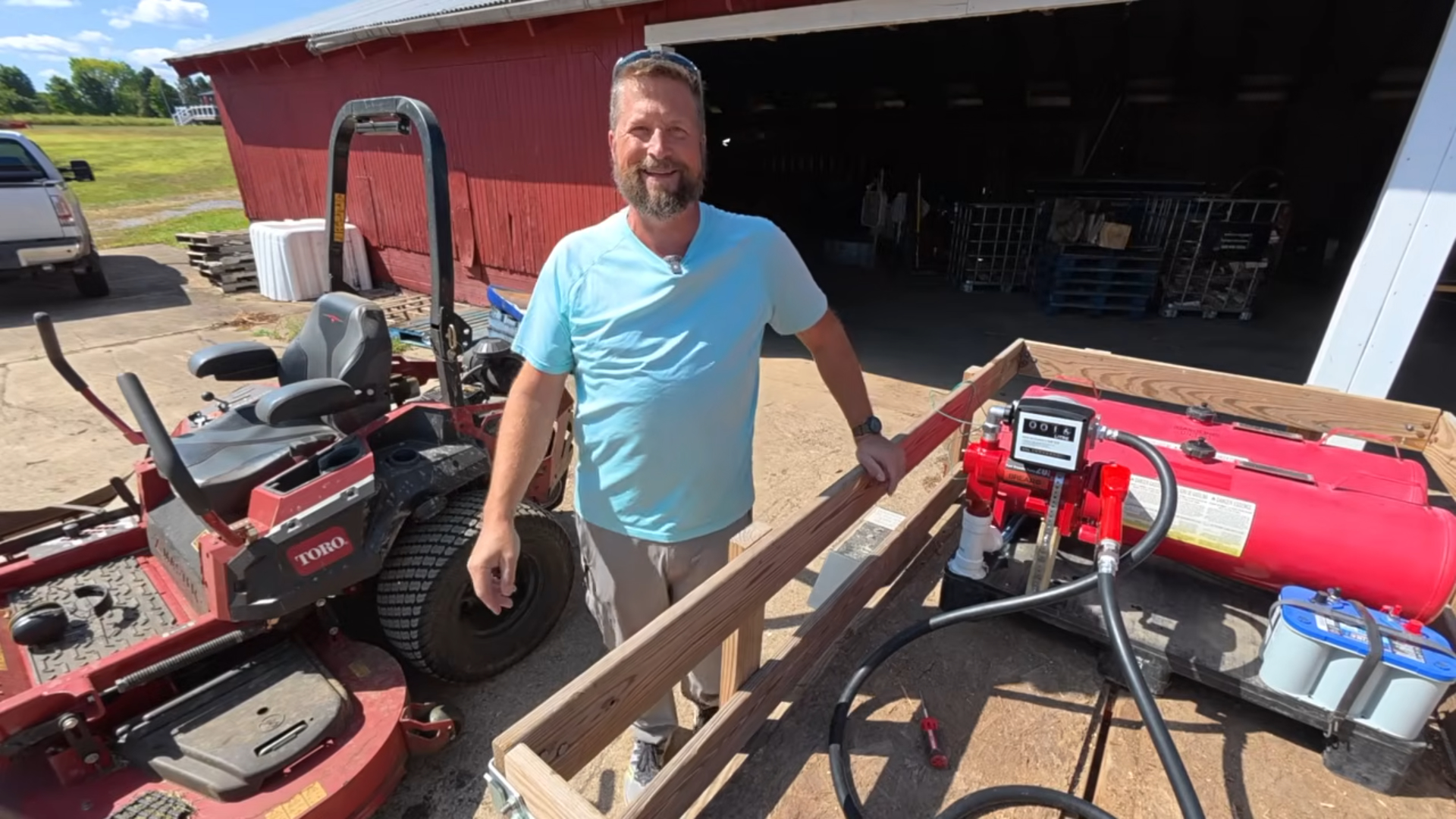 Farm operator standing next to a Brearo diesel fuel transfer pump and refueling setup at a farmyard.