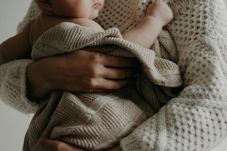 Woman holding her new-born baby in a blanket.