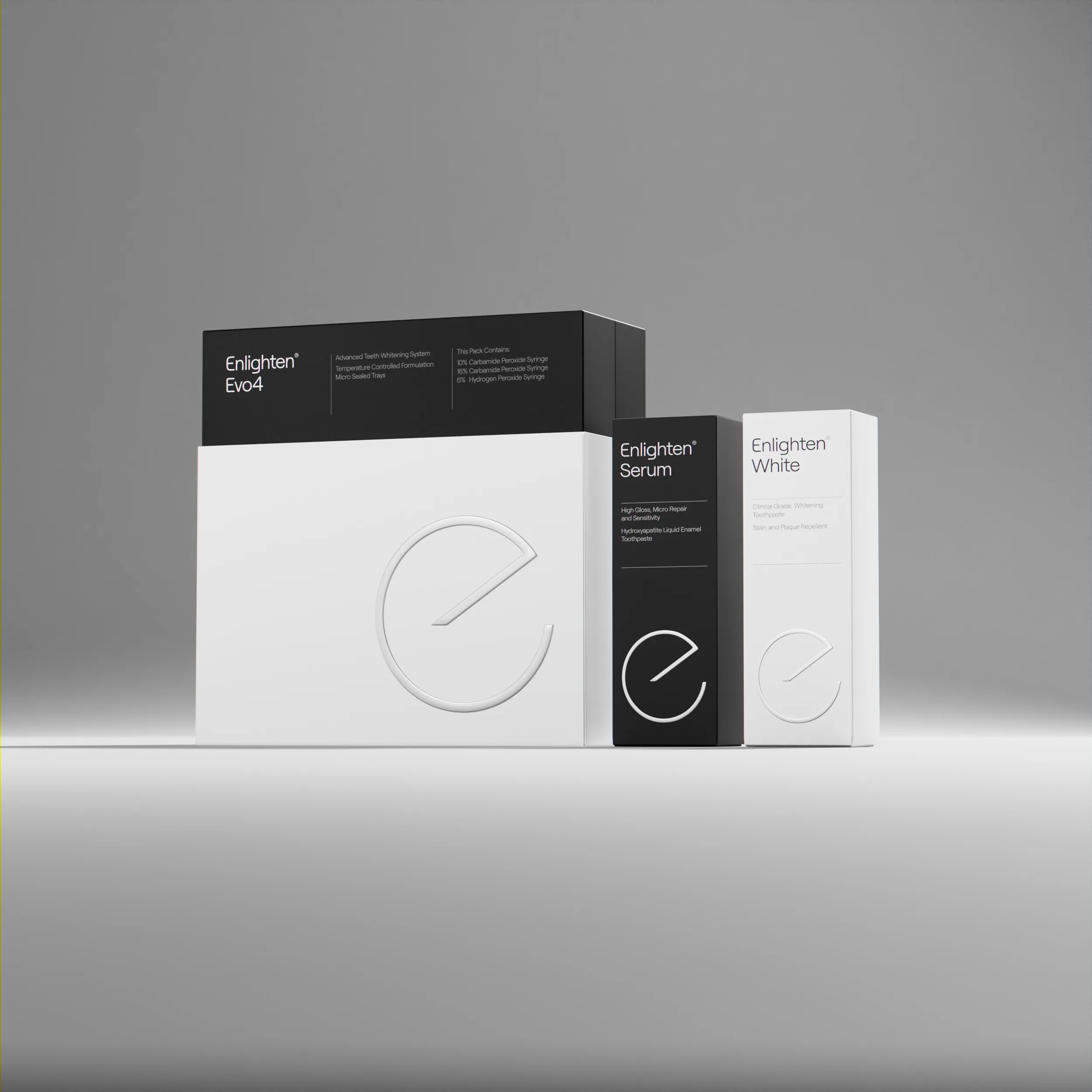 Product packaging for Enlighten teeth whitening system, featuring three sleek, modern boxes: Enlighten Evo4 whitening kit, Enlighten Serum toothpaste, and Enlighten White toothpaste. The design uses a minimalist black and white colour scheme with embossed branding and clean typography in a grey/white ish gradient background.