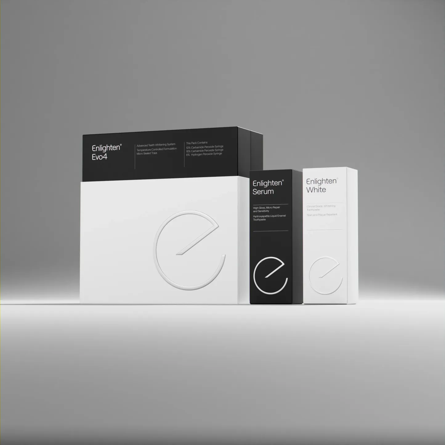 Product packaging for Enlighten teeth whitening system, featuring three sleek, modern boxes: Enlighten Evo4 whitening kit, Enlighten Serum toothpaste, and Enlighten White toothpaste. The design uses a minimalist black and white colour scheme with embossed branding and clean typography in a grey/white ish gradient background.
