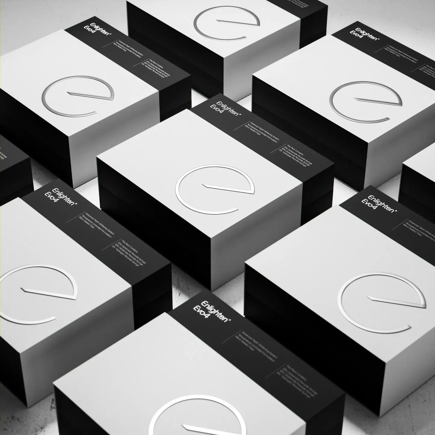 A pattern of Enlighten Evo4 Whitening System boxes arranged in a grid, showcasing their sleek design. Each box features a white front with the embossed silver Enlighten logo and a contrasting black side panel displaying product details. The minimalist, monochromatic aesthetic highlights the premium quality and modern branding. Set against a textured, light-gray surface, the arrangement emphasises uniformity and elegance.