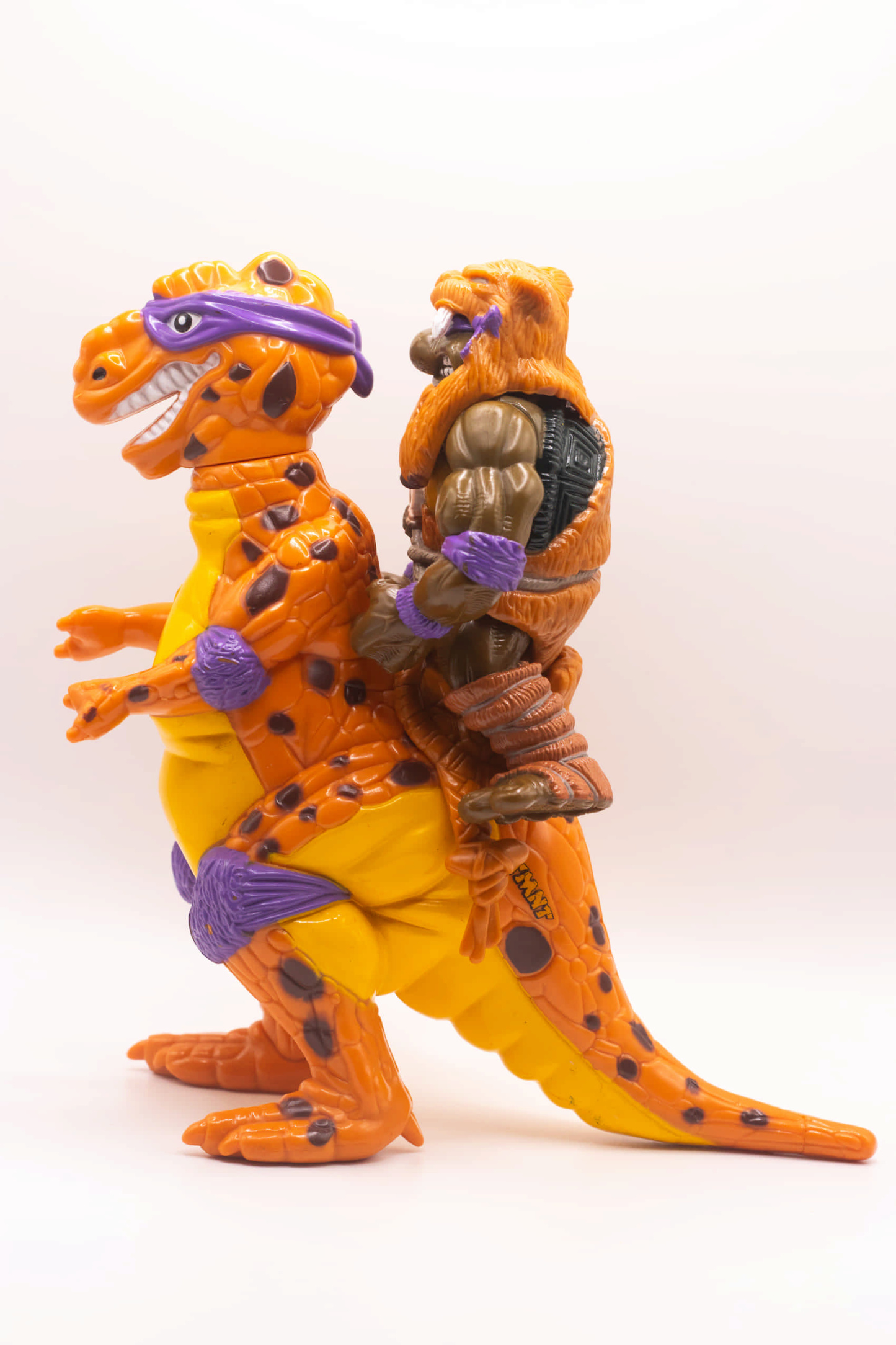 Left side view of vintage Cave-Turtle Don action figure holding Mesozoic Mace, riding on Trippy Tyrannosaurus