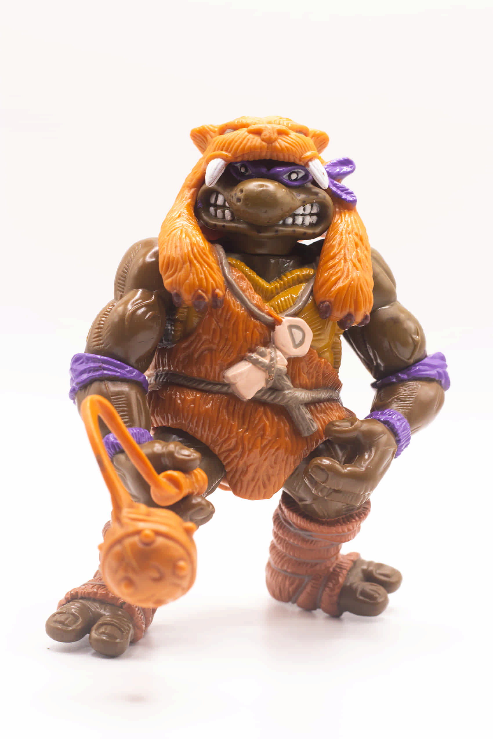 Front-facing shot of Cave-Turtle Don action figure holding Mesozoic Mace with D pendant visible