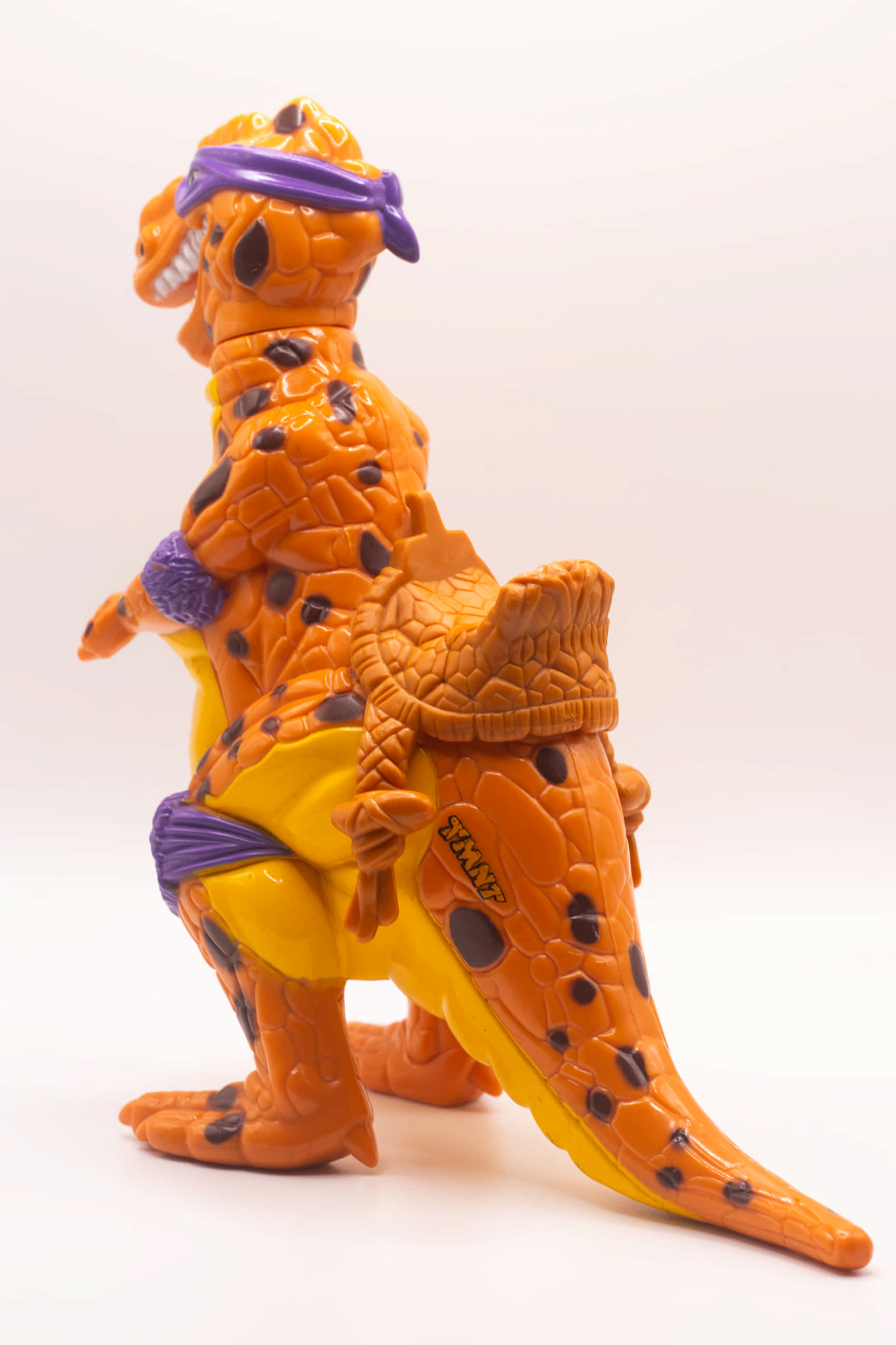 Rear left side view of Trippy Tyrannosaurus showing mounted saddle and TMNT logo on tail