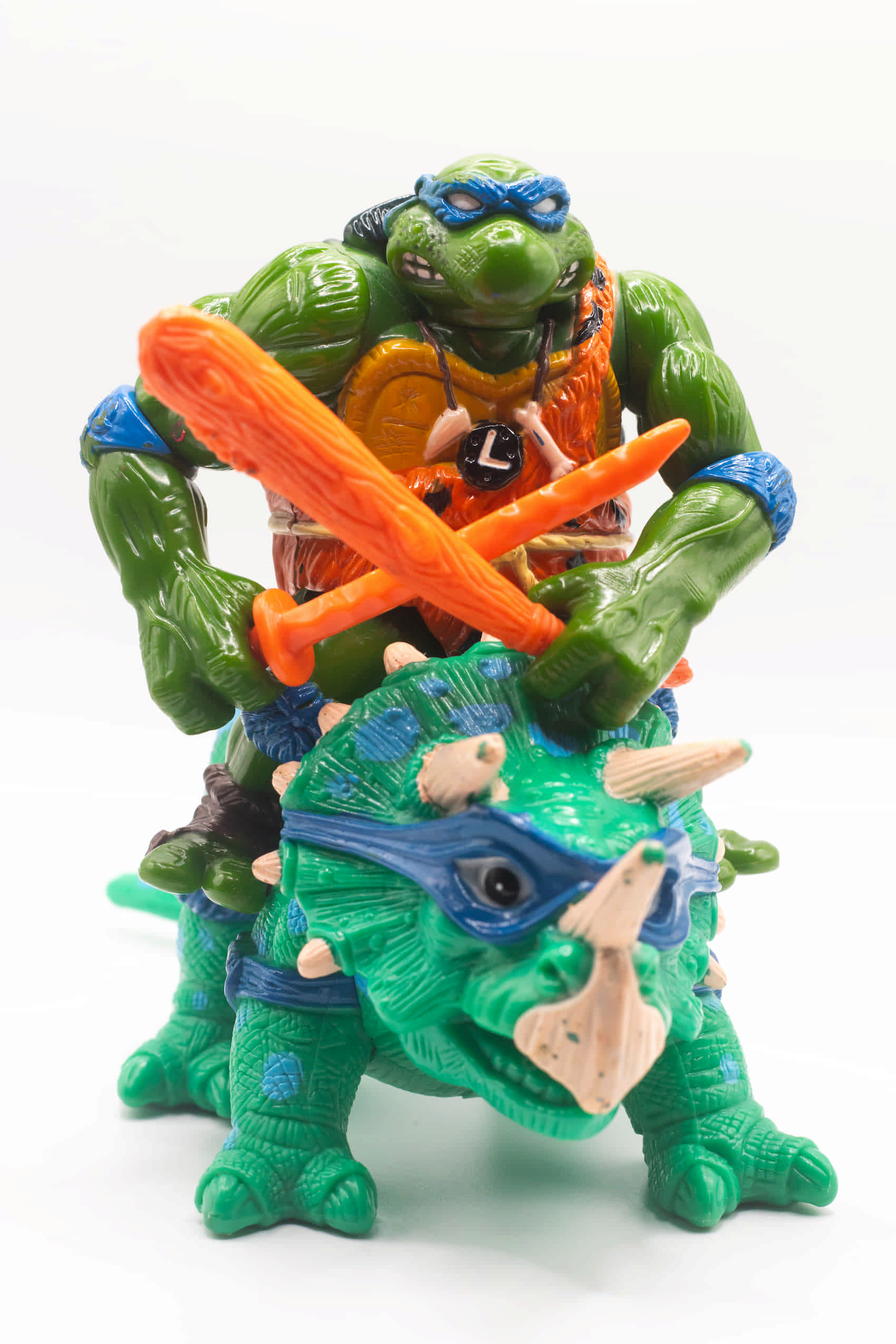 Face on shot of vintage Cave-Turtle Leo action figure holding katana and club, riding Dingy Dino