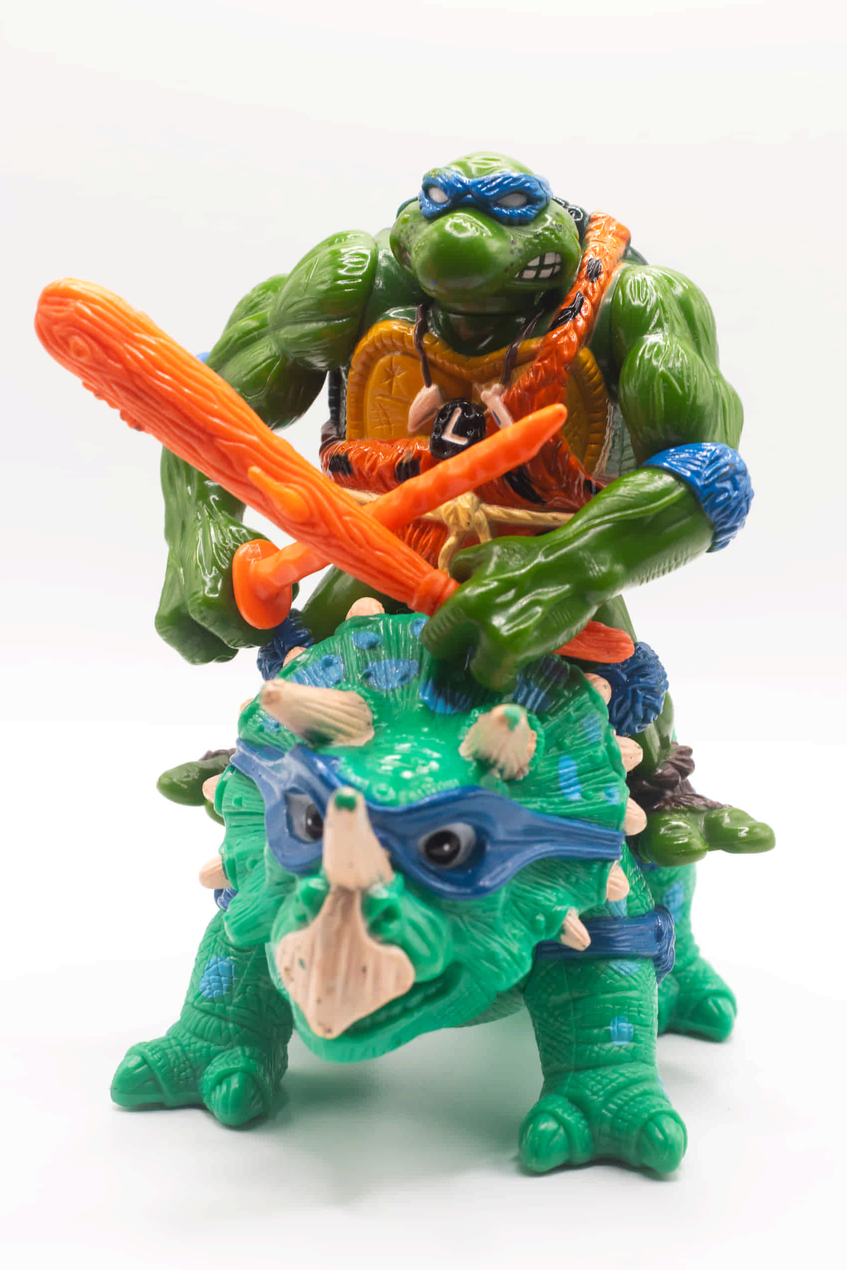 Face on shot of vintage Cave-Turtle Leo action figure holding katana and club, riding Dingy Dino