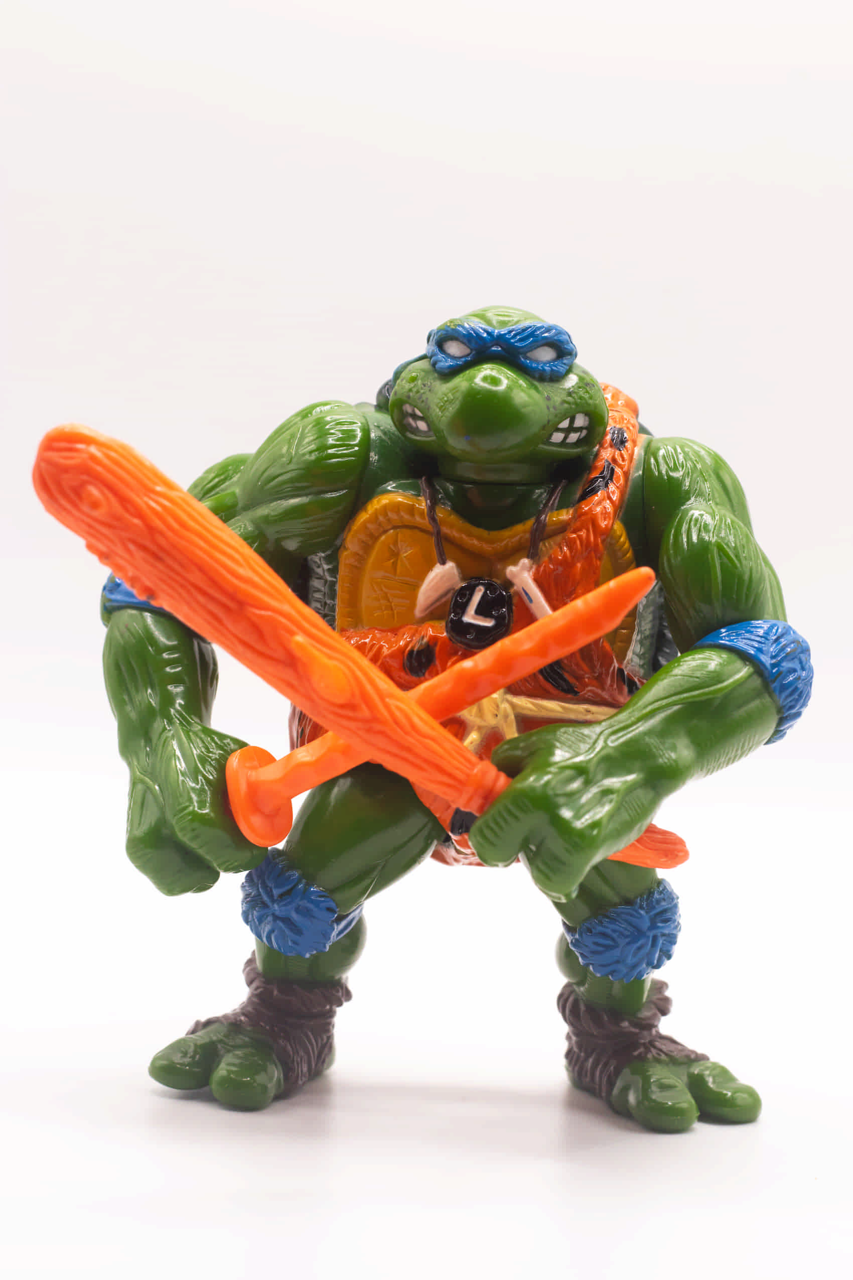 Face on shot of vintage Cave-Turtle Leo action figure holding katana and club crossed in front