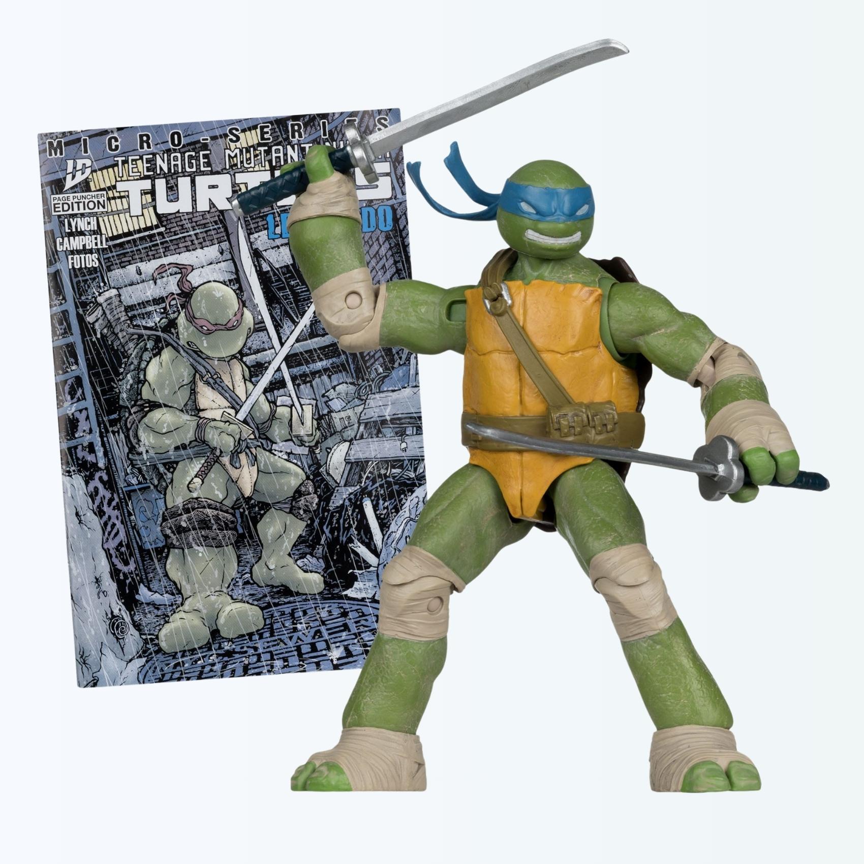 Dynamic front-angle shot of Leonardo action figure wielding twin katanas with the included comic behind