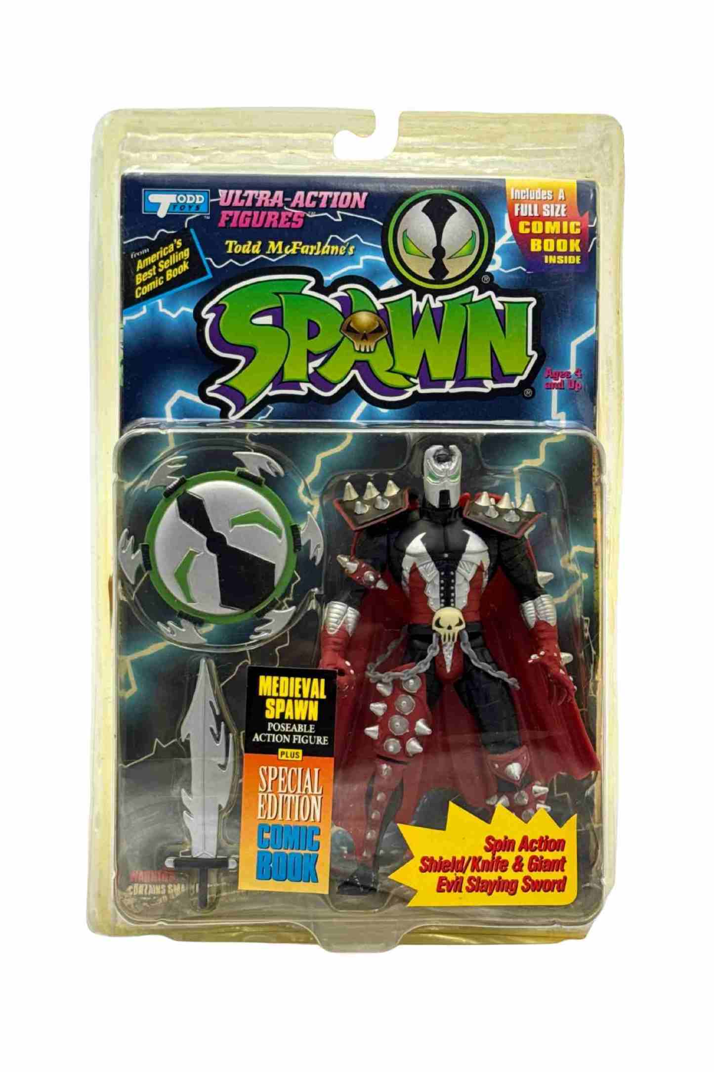 Front carded shot of Medieval Spawn action figure in black and silver armour with red cape, spiked shoulder pads, spinning shield and giant sword accessory in blister packaging