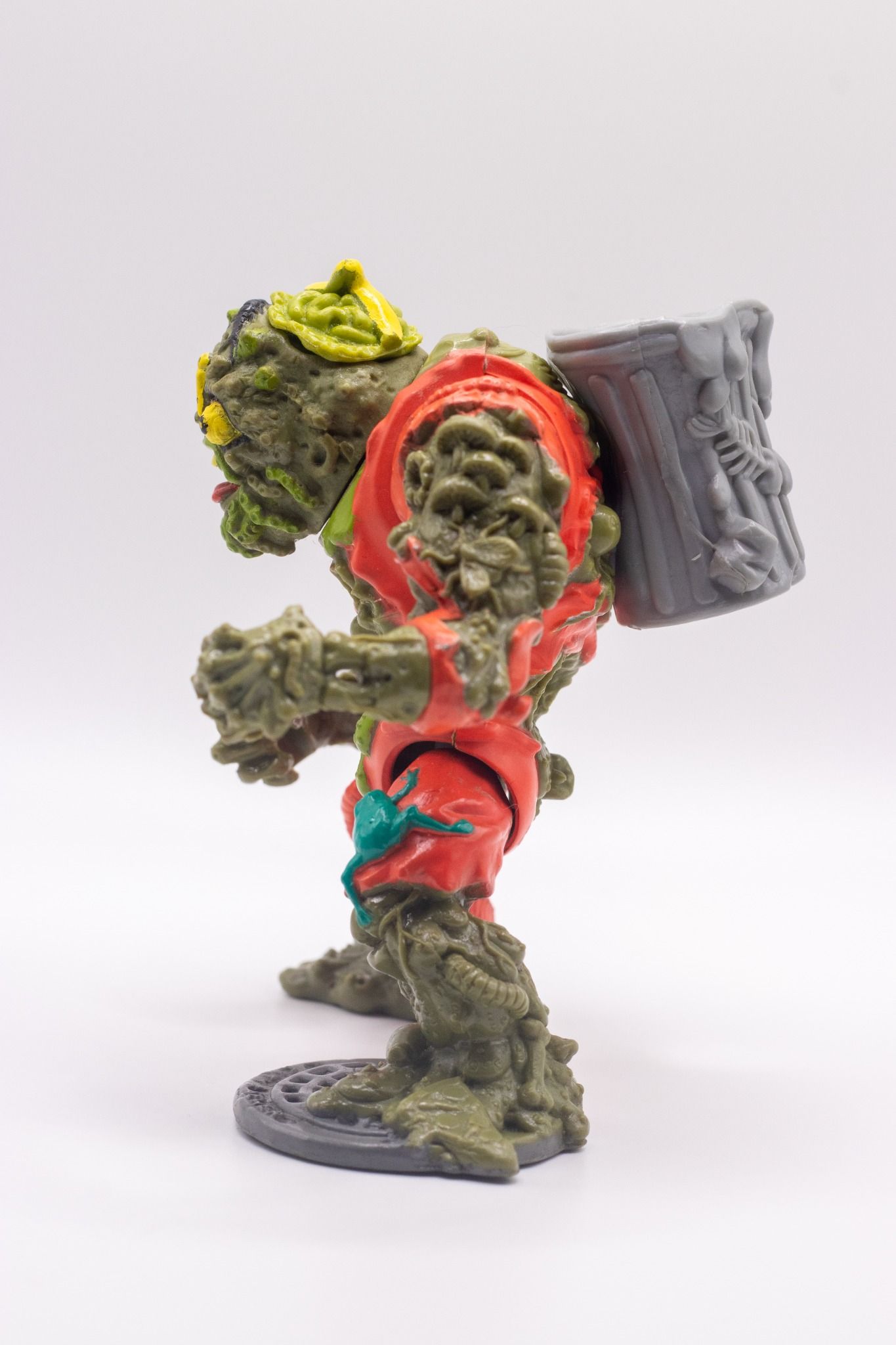 Left side profile of TMNT Muckman action figure showing attached trash can backpack