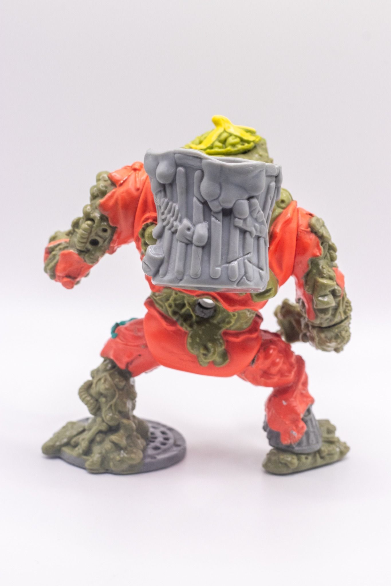 Rear view of TMNT Muckman action figure with large grey trash can backpack