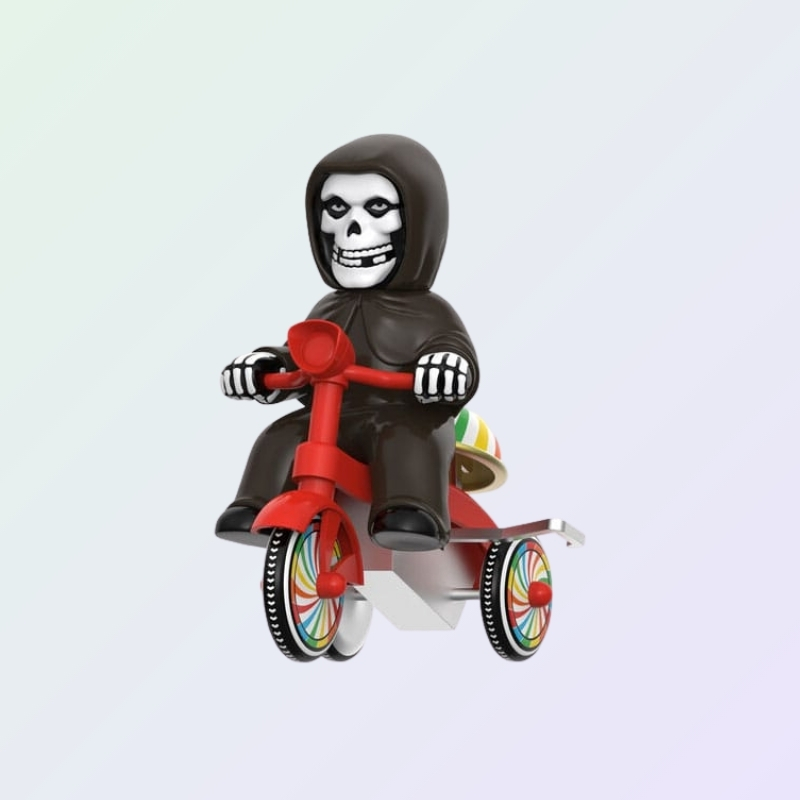 Angled view of Misfits The Fiend figure riding tricycle with rainbow wheels and black cloak