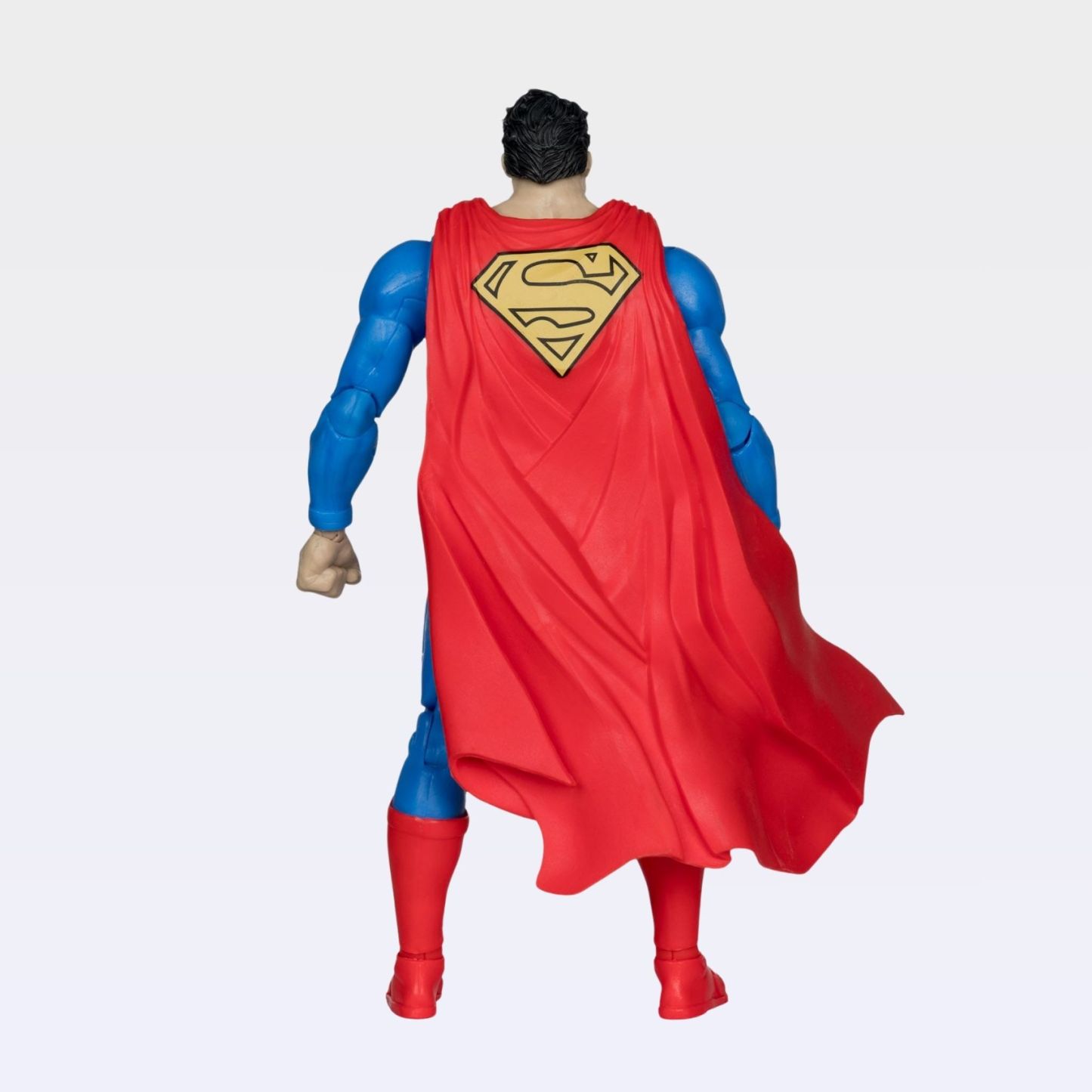 Back-angle view of Superman Hush action figure highlighting yellow S emblem and cape folds