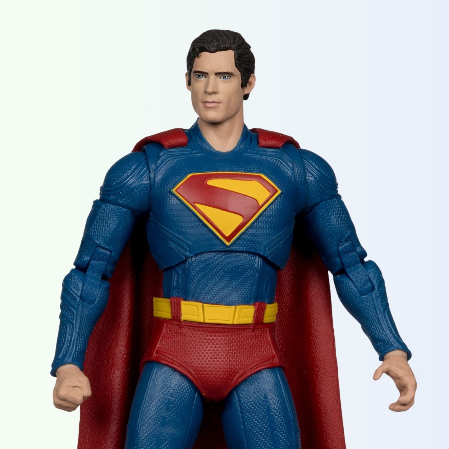 Front-facing shot of Superman action figure with fist clenched, showing chest emblem and textured suit